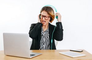 Woman wearing headphones startled by loud noise, takes them off to look after your hearing health