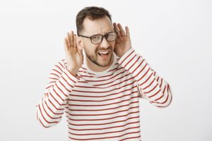 Man raising his hands to his ears signalling that he cant hear properly