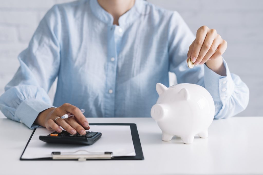 Woman saving money, putting coins into a piggy bank