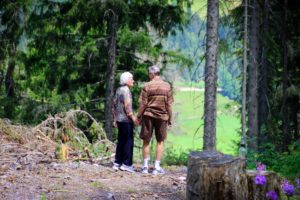 Senior couple wearing hearing aids, talking a walk outside in the forest.