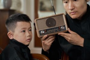 child and son listening closely to the radio