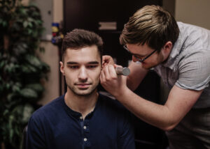 Hearing aid practitioner performing a hearing test on a younger male patient