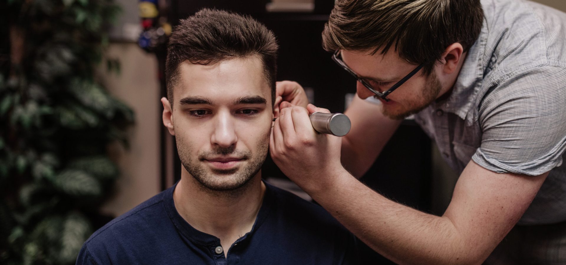 Hearing aid practitioner performing a hearing test on a younger male patient