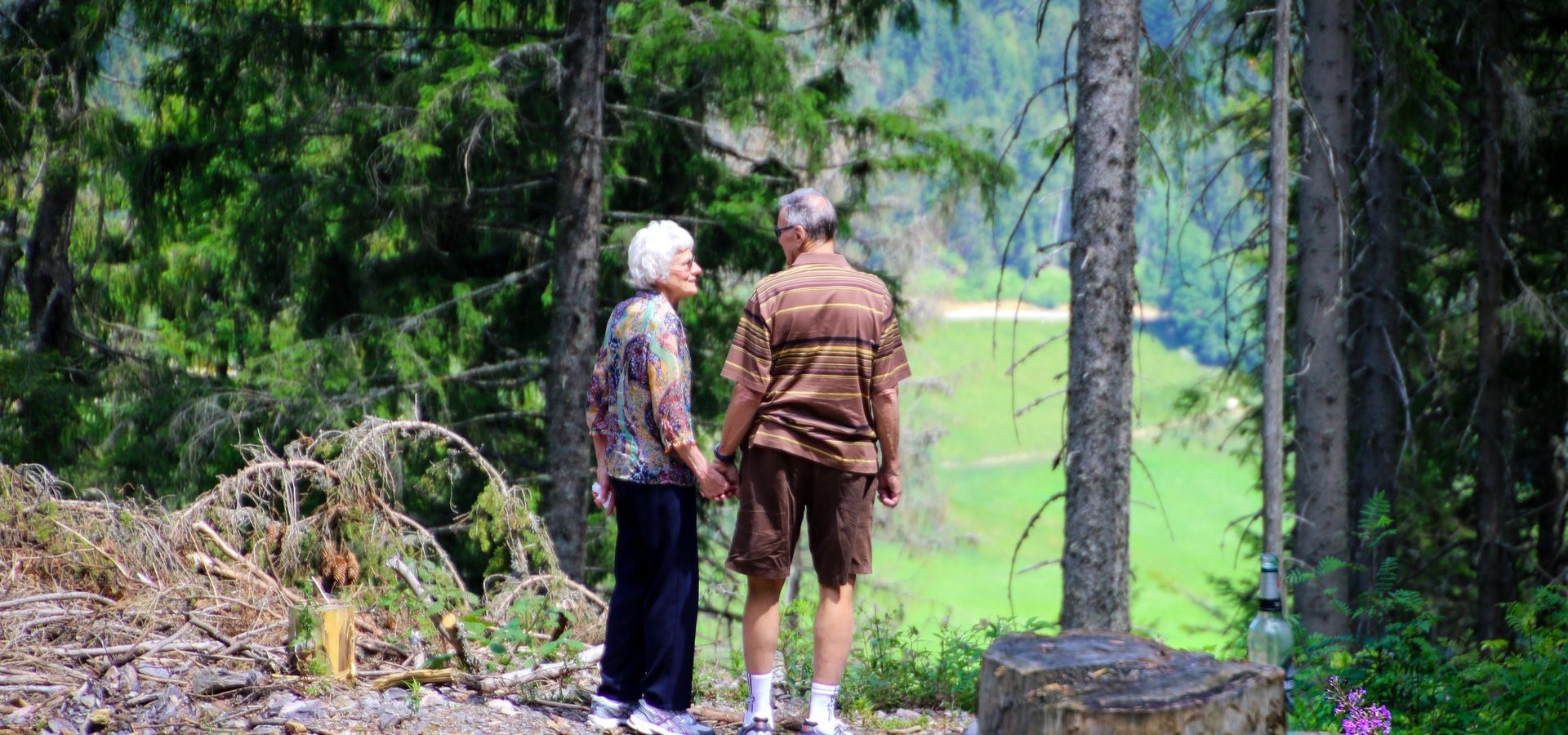 Senior couple wearing hearing aids, talking a walk outside in the forest.