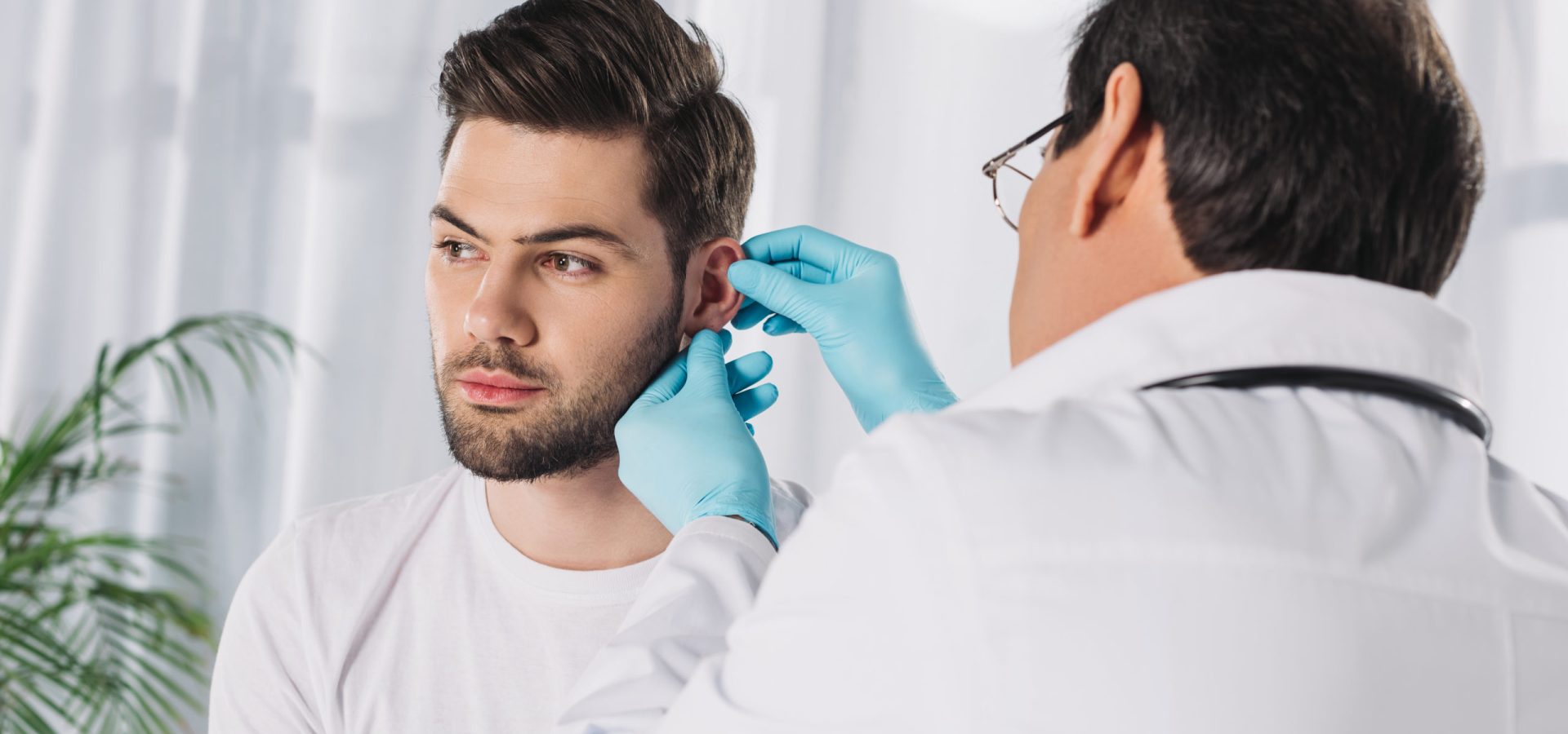 doctor examining male patient ear