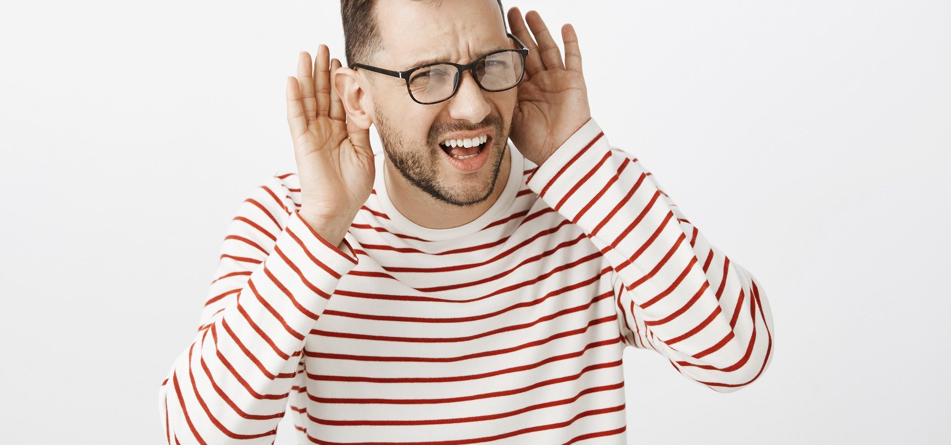 Man raising his hands to his ears signalling that he cant hear properly
