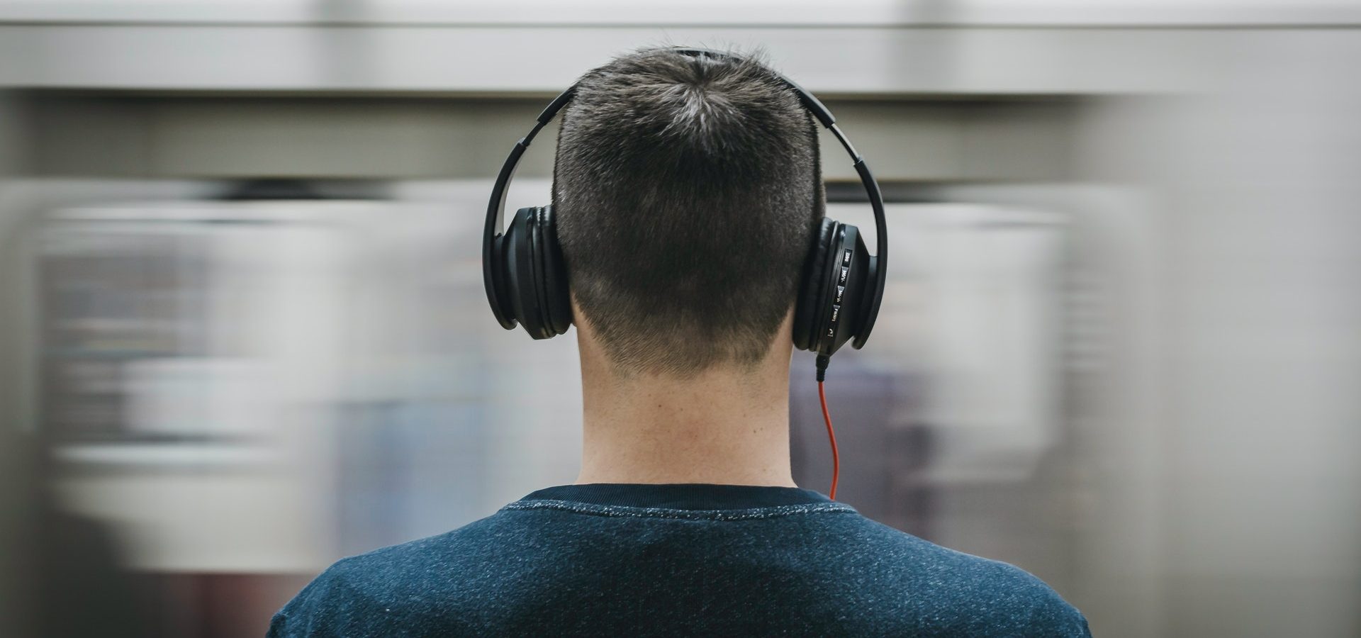 Man in public listening to loud music through his headphones, potentially causing noise-induced hearing loss
