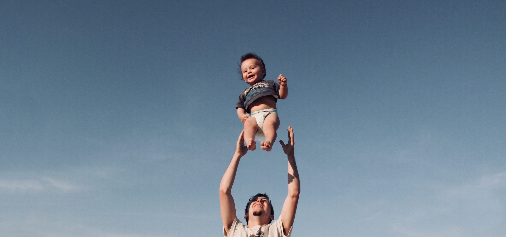 Dad raising his son in the air on a sunny day