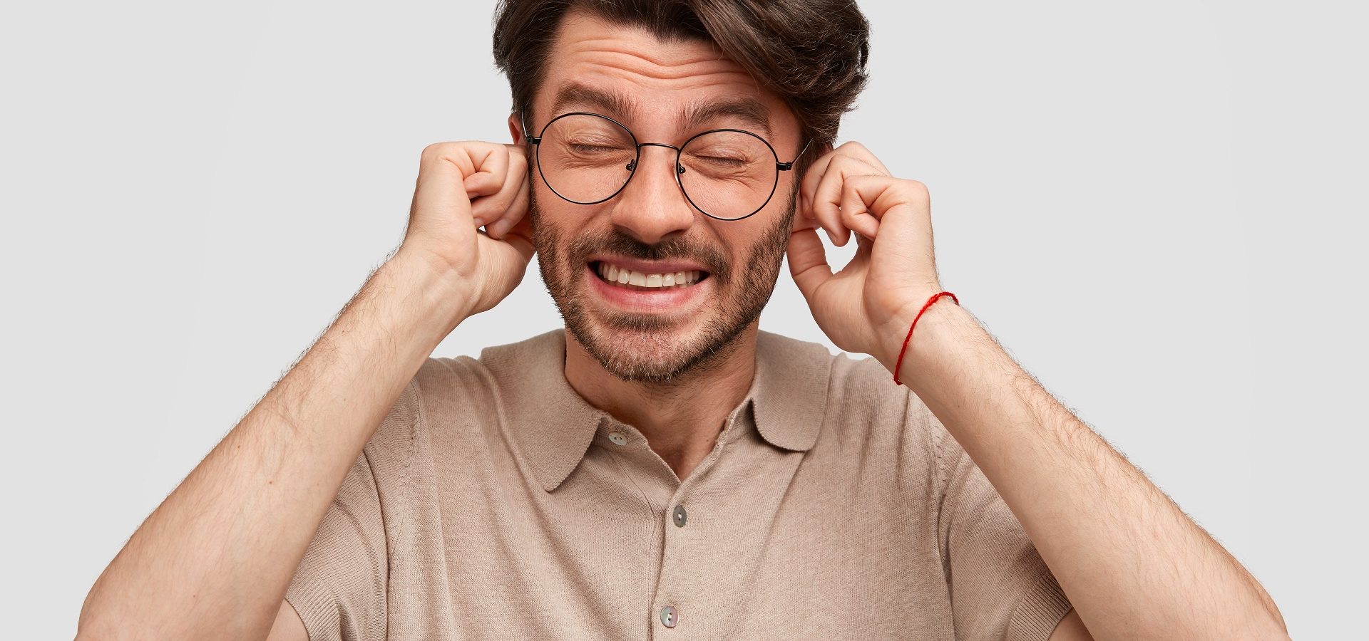 Photo of man suffering from tinnitus plugging his ears