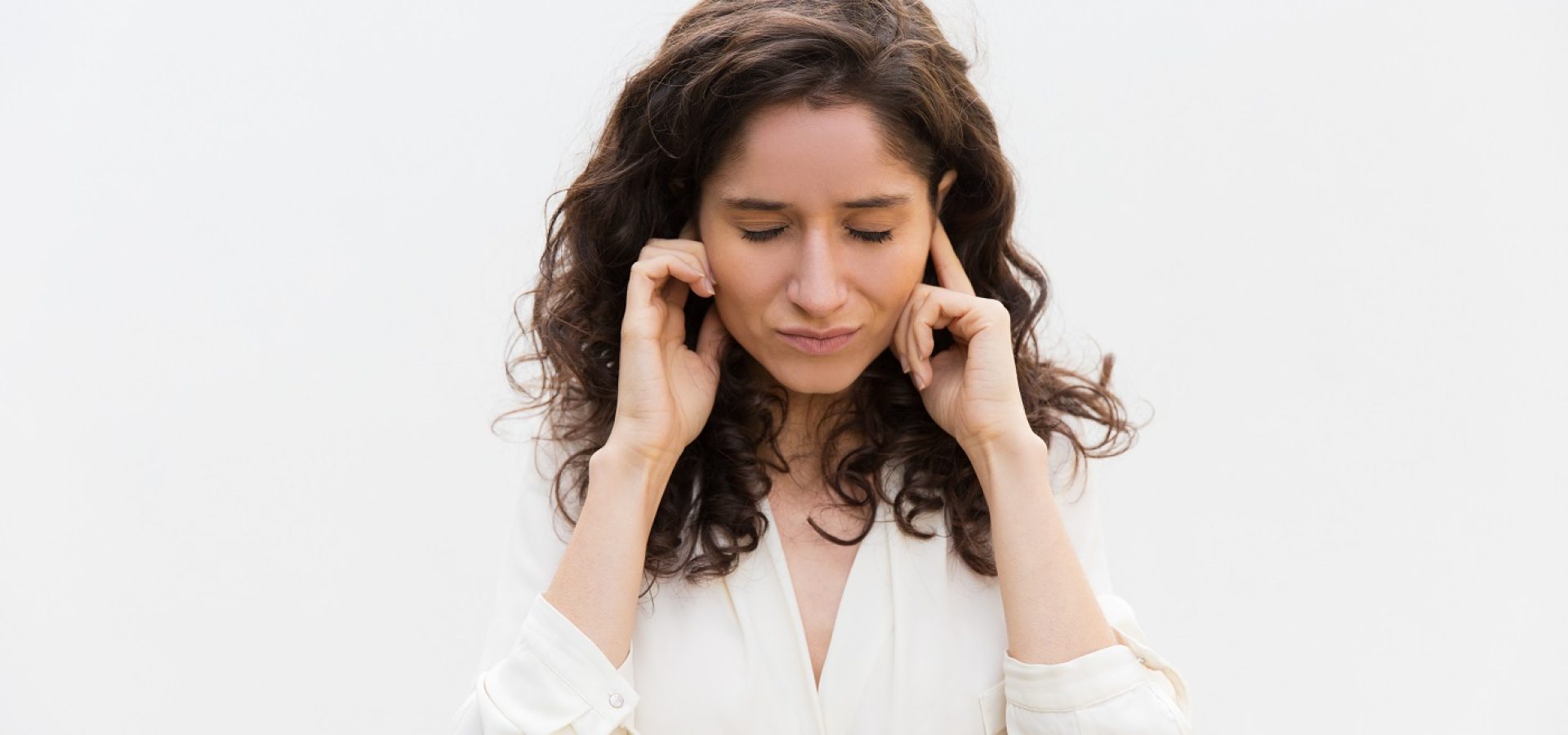 Woman plugging her ears, symbolizing they are clogged