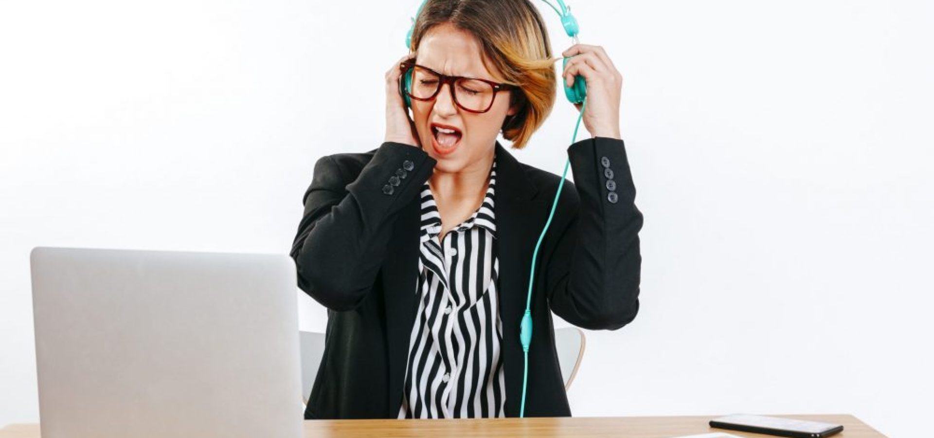 Woman wearing headphones startled by loud noise, takes them off to look after your hearing health