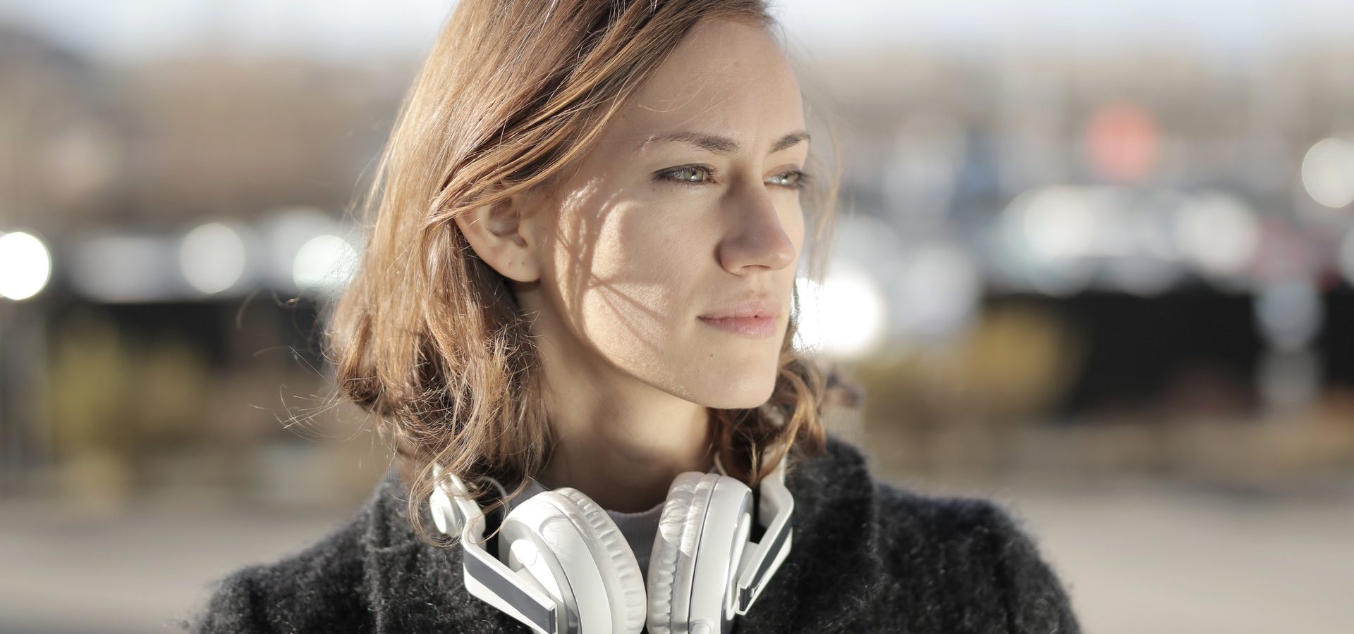 Woman with headphones around her neck outside